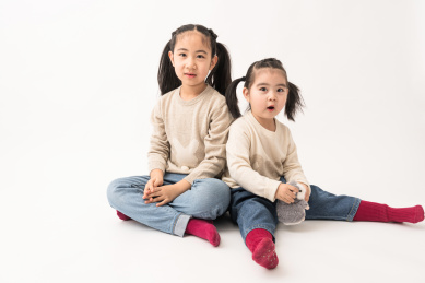 两名坐在白色背景前玩耍的姐妹