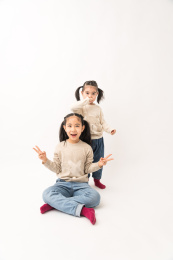 两名坐在白色背景前玩耍的姐妹