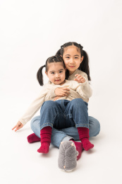 两名坐在白色背景前玩耍的姐妹