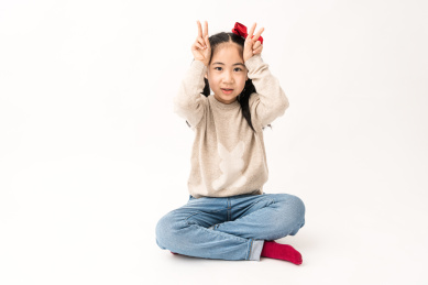 坐在白色背景前玩耍的中国女孩