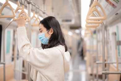 戴口罩坐地铁的女生站着抓着扶手