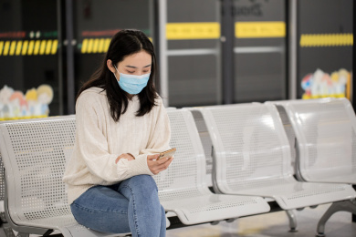 年轻女性戴着口罩坐着看手机等地铁