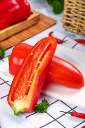 白石板上放着一个完整红甜椒和半边辣椒