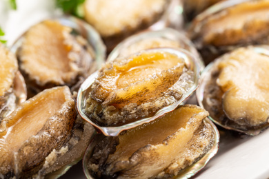 木板背景上满满一盘新鲜鲍鱼