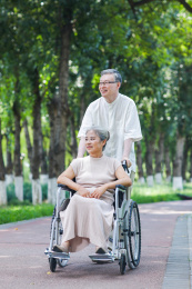 老年男人推着坐轮椅的老伴