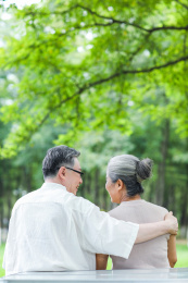幸福的老年夫妇坐在户外公园的椅子上