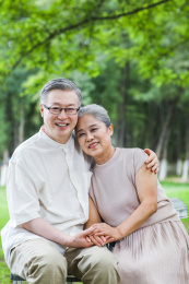 幸福的老年夫妇坐在户外公园的椅子上