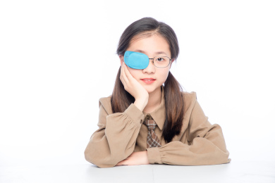 白色背景里，带着弱视眼罩的亚洲小女孩
