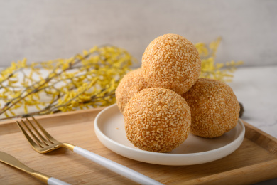 桌面上的白色陶瓷盘子里的美味可口的煎堆