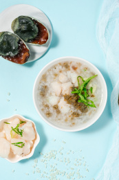 浅色背景下放在蓝色卡纸上的皮蛋鱼肉粥