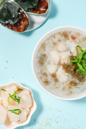 浅色背景下放在蓝色卡纸上的皮蛋鱼肉粥