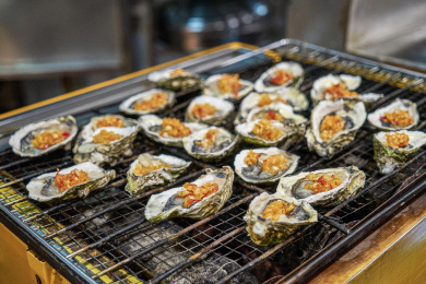 正在烹饪的蒜香烤生蚝整齐的摆放在烧烤炉上