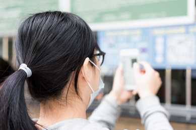 佩戴口罩的女子使用手机购票