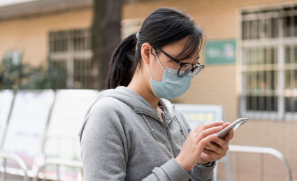 佩戴口罩的女子使用手机购票