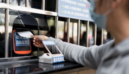 佩戴口罩的女子使用手机购票