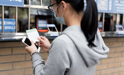 佩戴口罩的女子使用手机购票