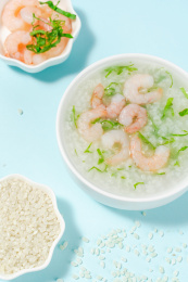 浅色背景下放在蓝色卡纸上的虾仁青菜粥