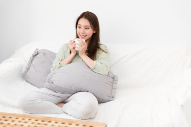 年轻女性拿着水杯坐在客厅沙发上看电视