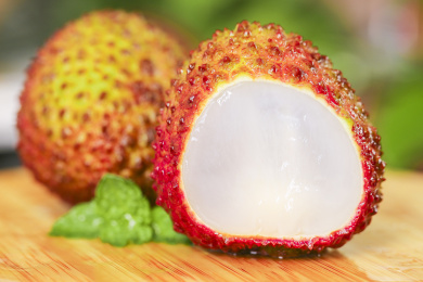 木底上放着一颗完整的鲜荔枝和半边丹荔