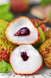 盘子里放着一堆新鲜荔枝和两个半边的丹荔