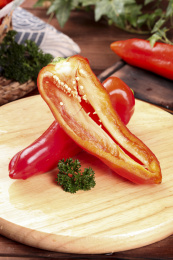 木板上放着一个完整的大红椒和半边土辣椒