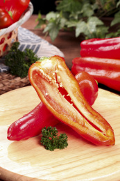 木板上放着一个完整的大红椒和半边土辣椒