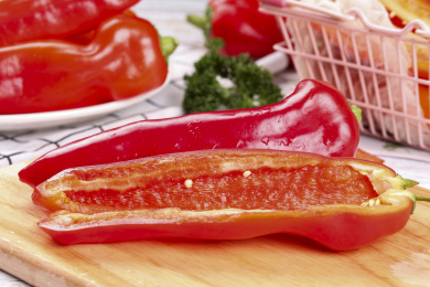 木板上放着一个完整的大红椒和半边土辣椒