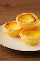 实木桌上摆着的一盘葡式蛋挞