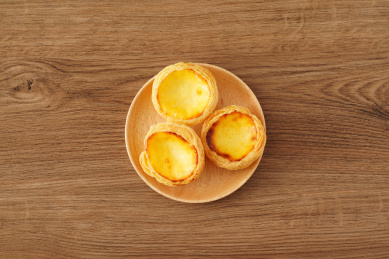 实木桌上摆着的一盘葡式蛋挞