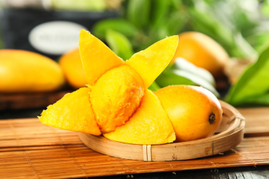 竹底上蓝子里的台农芒和一个撕开皮的芒果