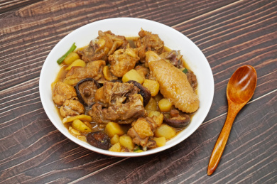 木桌背景中一盘土豆焖鸡肉