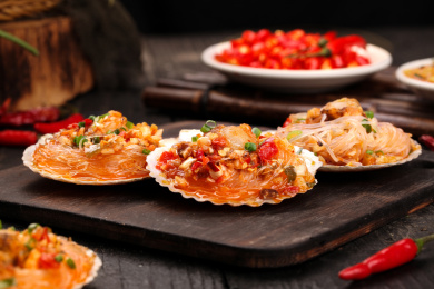 黑底上放着蒜蓉剁椒蒸扇贝