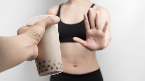 女性对着递过来的奶茶做拒绝手势