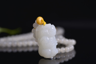 黑色背景上的和田玉吊坠，龙雕件