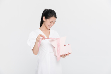穿着白色裙子的女孩收到礼物开心打开礼物