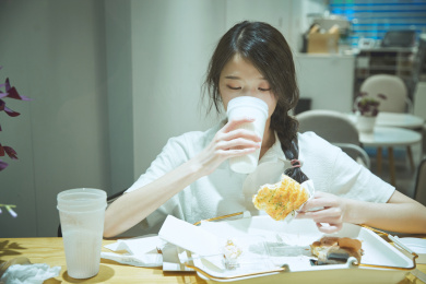 在烘焙店吃面包喝牛奶的可爱亚洲少女