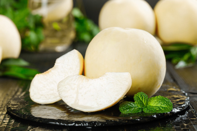 黑石板上放着白桃和切块的桃子果肉