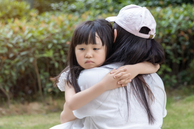 在户外情绪失落的小女孩搂着妈妈脖子