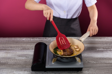 用红色硅胶铲在卡式炉灶上煎牛排