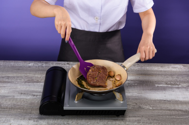 用紫色硅胶铲在卡式炉灶上煎牛排