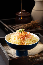 高脚碗里的正在倒入红油辣子的麻辣鸡丝凉面