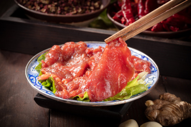 筷子夹着的重庆老火锅菜品嫩牛肉片
