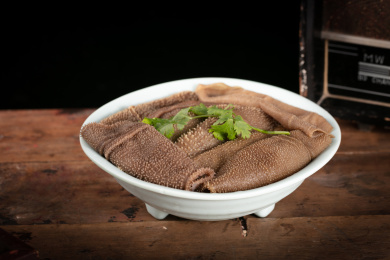 木桌上的白盘里的重庆火锅菜品毛肚