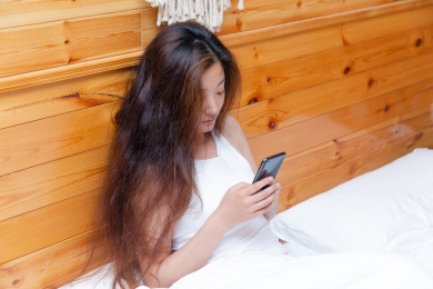 靠在床头看手机的中国女孩