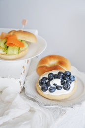 盘子里放着的贝果夹酸奶蓝莓