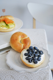 盘子里放着的贝果夹酸奶蓝莓