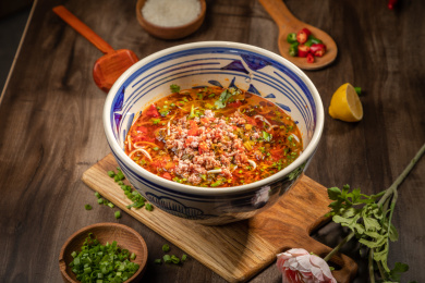 棕色桌面上放着一碗红油肉末米线