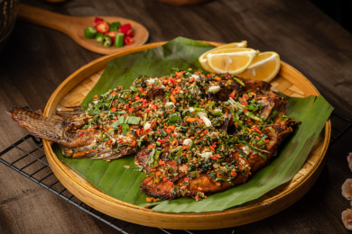 棕色桌面上放着一盘香茅草烤鱼