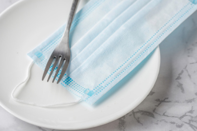 餐叉和白色瓷盘里的一次性医用口罩