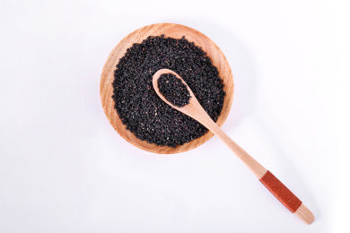 白色背景上木盘子里的黑芝麻